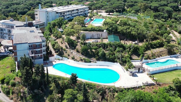 A resort with a large swimming pool, multiple buildings, and lush greenery. - Residenza Verde Blu - Verde Blu Primo Piano (620) (Capoliveri)