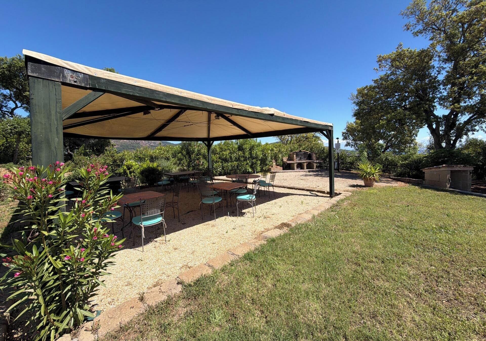 An outdoor patio area with a covered seating arrangement and a barbecue setup.