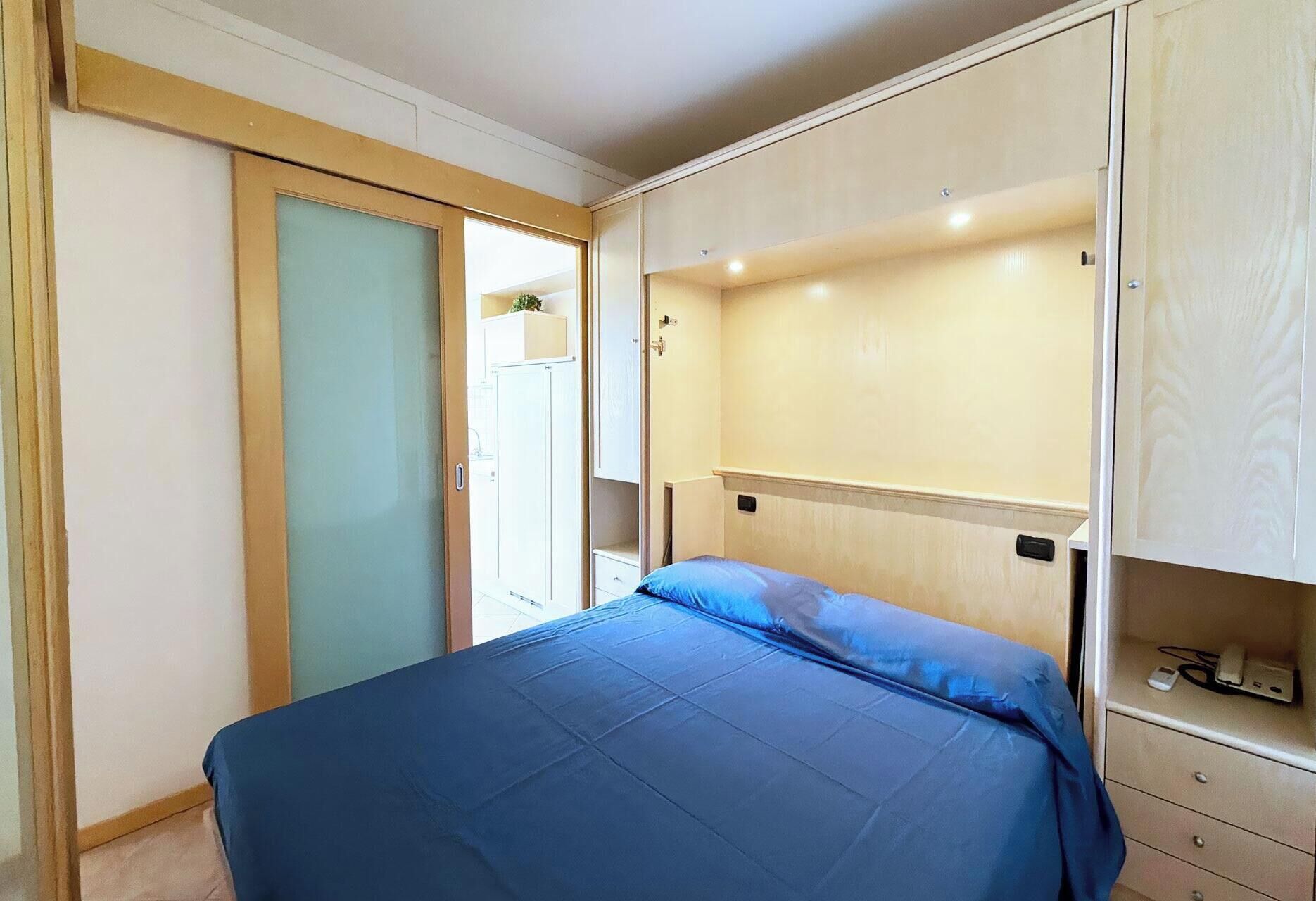 Une chambre à coucher comprenant un lit, une armoire et un petit espace bureau.