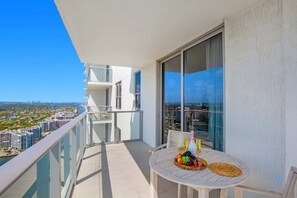 A balcony with a table set for a meal, overlooking a cityscape. - Luxury Beach Condo • Stunning Views (Hollywood)