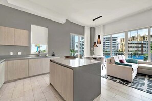 Eine moderne Wohnung mit Küche, Essbereich und Wohnzimmer, ausgestattet mit großen Fenstern und Blick auf die Stadt.