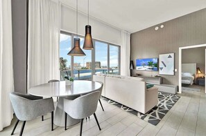 Ein modernes Hotelzimmer mit Essbereich, einer Couch, einem Fernseher und Blick auf die Stadt.