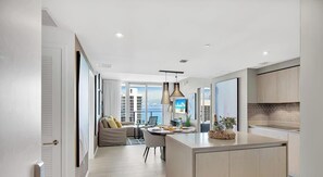 A modern kitchen with a central island, pendant lighting, and a view of the city. - Oceanfront Balcony • Pools & Gym (Hollywood)