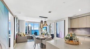 A modern kitchen with a dining area, large windows, and a view of the city. - Oceanfront Balcony • Pools & Gym (Hollywood)