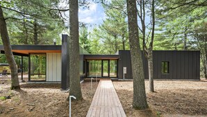 Eine moderne Holzhütte mit einer Holzterrasse, umgeben von Bäumen.