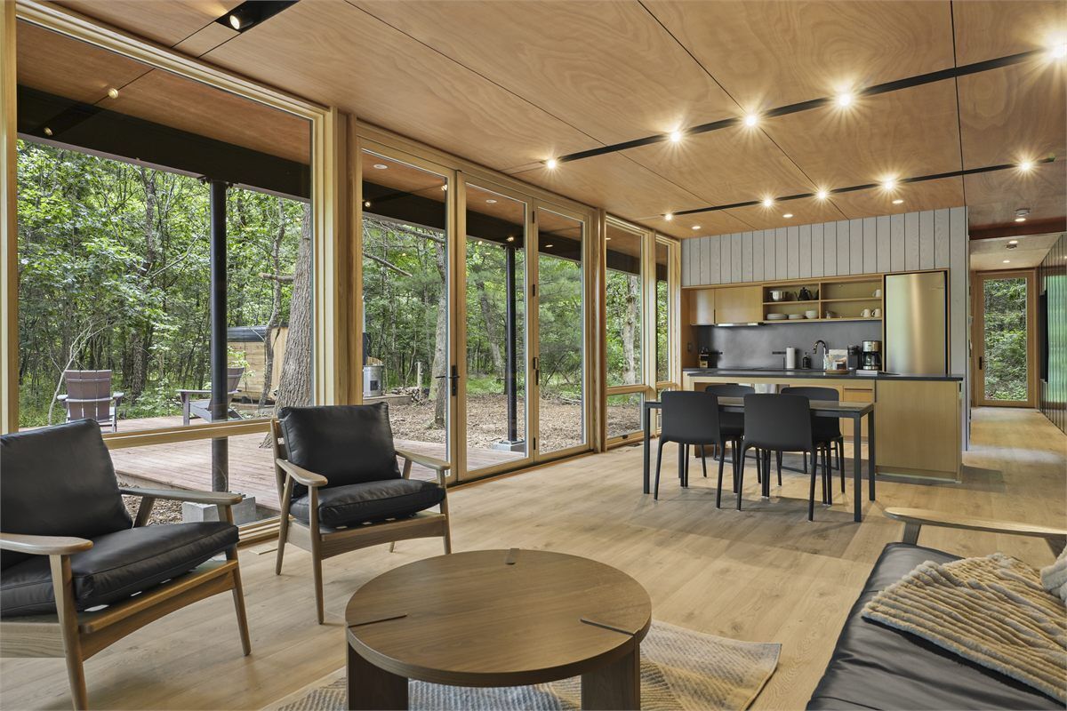 A modern interior with large windows, a dining area, and a kitchen.