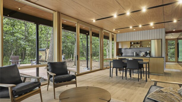 Ein modernes Interieur mit großen Fenstern, einem Essbereich und einer Küche.