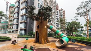 A playground with a slide and seesaw, surrounded by a large tree and modern buildings. - Midhills Genting by Manhattan (Genting Highlands)