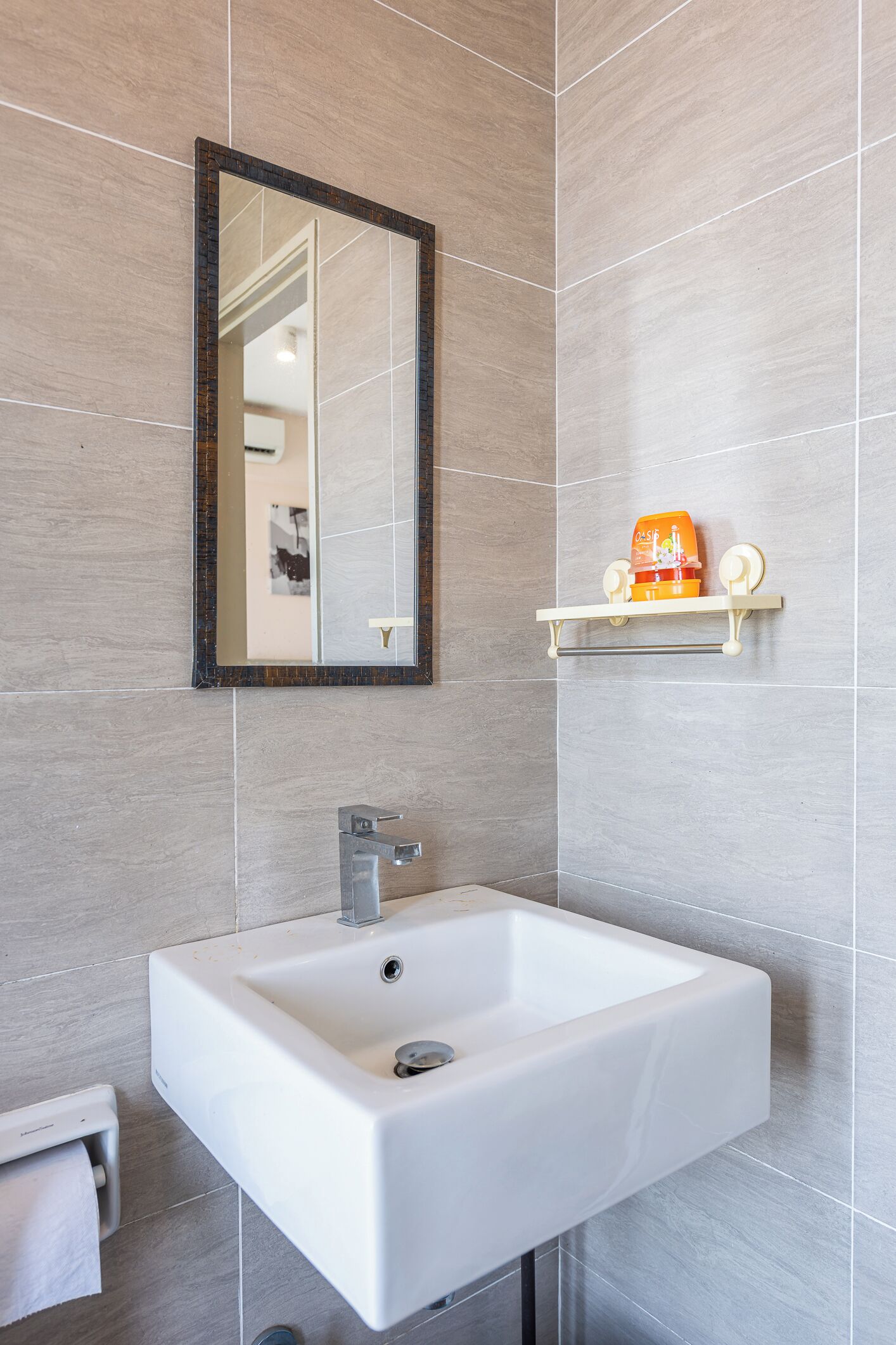 A bathroom with a white sink, a mirror, and a towel dispenser.