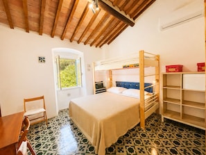 A room with a bunk bed, a desk, a chair, a window, and a tiled floor. - Bilocale Barbarossa a Porto Azzurro (Porto Azzurro)
