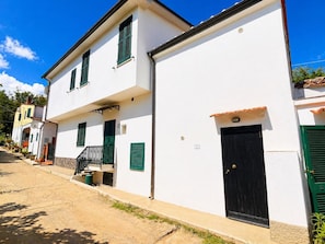 A white building with a black door, green shutters, and a small balcony. - Bilocale Barbarossa a Porto Azzurro (Porto Azzurro)