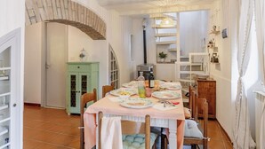 Un coin repas avec une table dressée pour quatre personnes, un buffet vert et un escalier menant à une autre pièce.