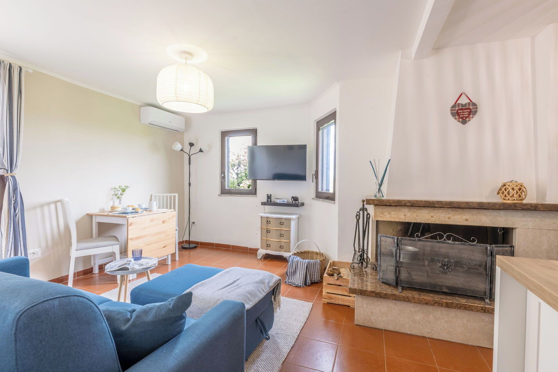 A living room with a sofa, a TV, a fireplace, and a dining area with a table and chairs.