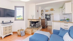 Un salon avec un téléviseur, un canapé et une cheminée.