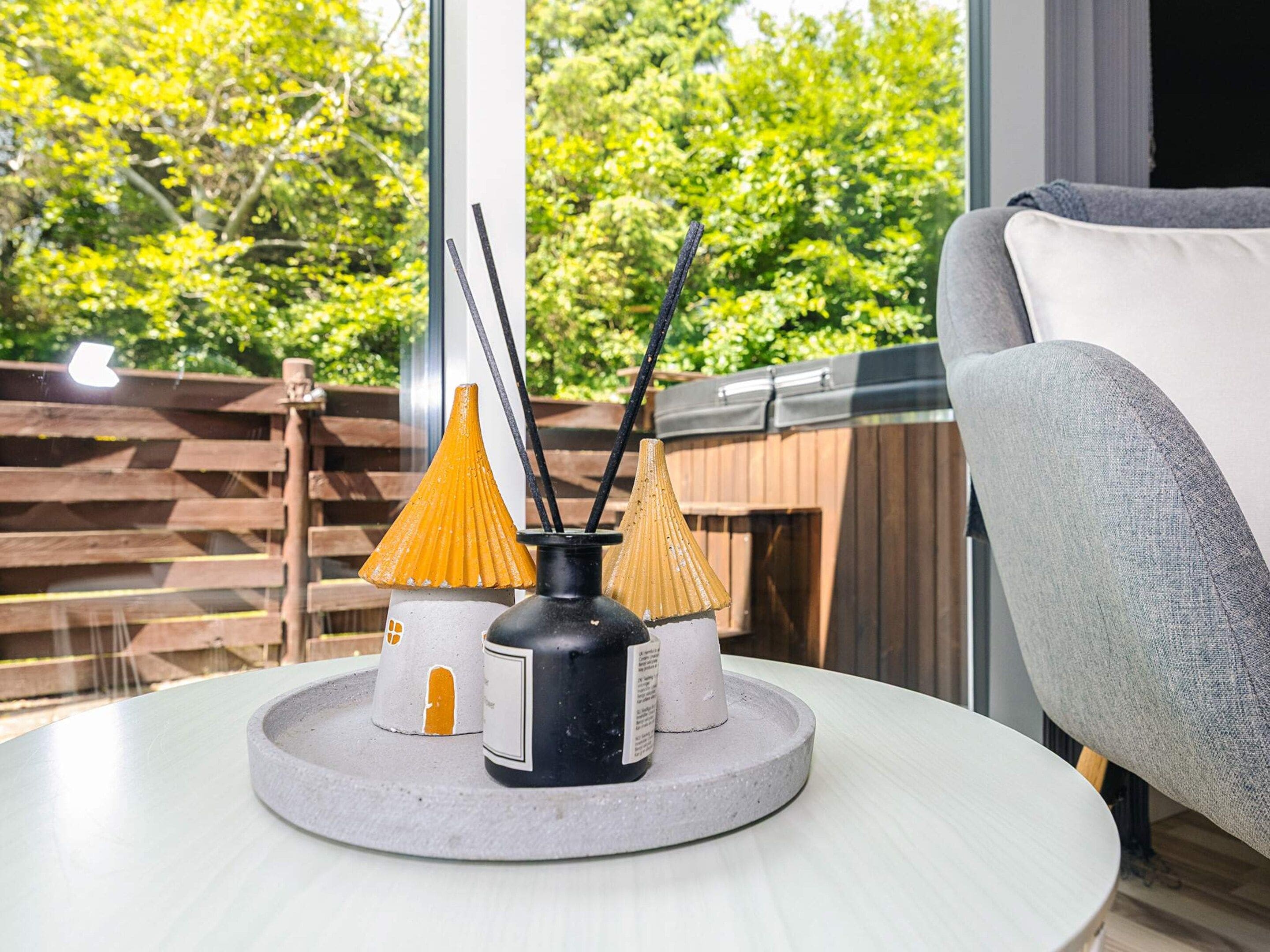 A round table with a modern chair, a decorative tray, and three conical vases with black stencils.