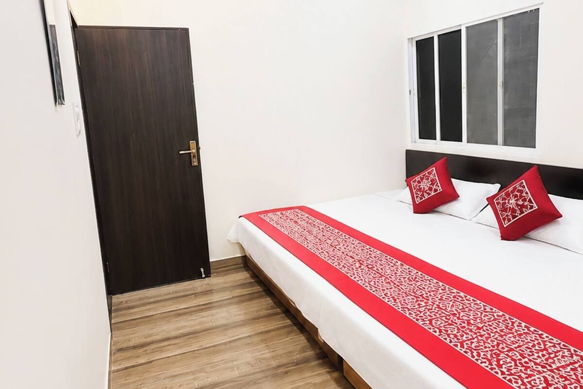 Ein Hotelzimmer mit Bett, Deckenventilator, Klimaanlage, Holztür und Fenster.