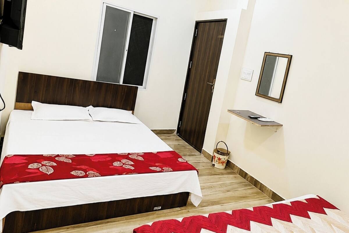 Ein Hotelzimmer mit zwei Betten, einem Deckenventilator, einer Klimaanlage, einem Fernseher und einem Spiegel.
