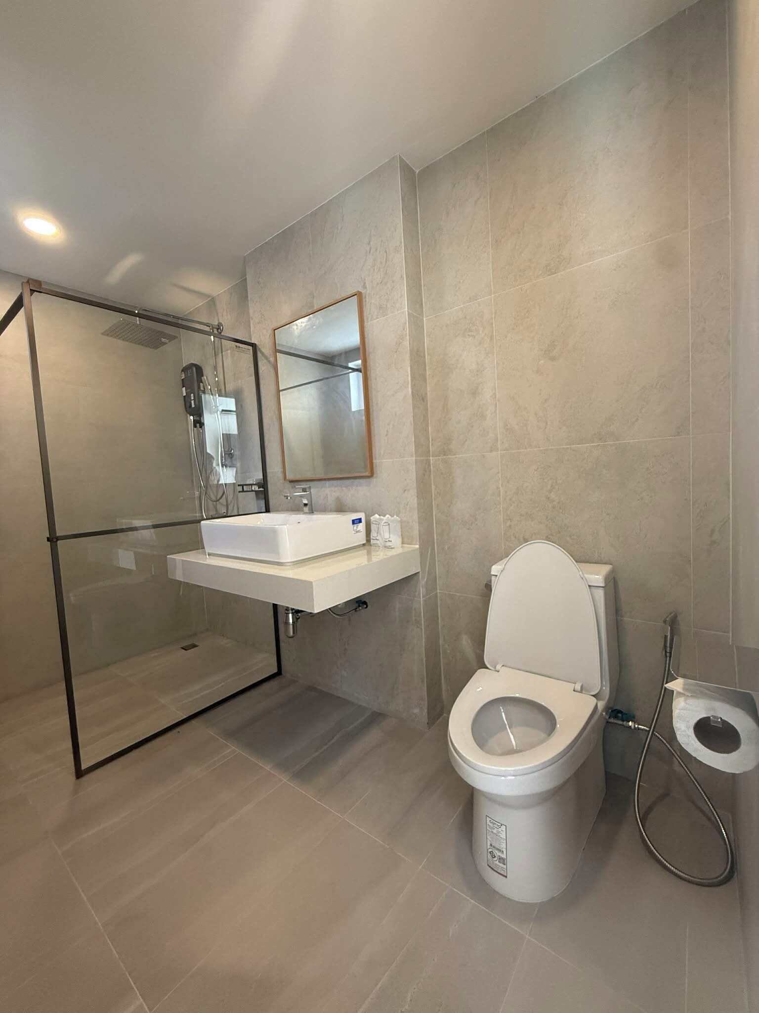 A modern bathroom with a glass shower enclosure, a white sink, and a toilet.