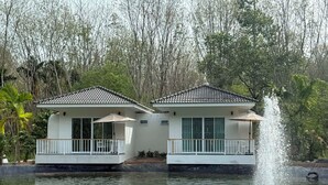 Dos edificios blancos con tejados de tejas, una fuente de agua y un estanque.