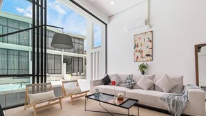 A modern living room with a sofa, coffee table, and chairs, large windows, and a balcony. - Elegant Pool Access Townhouse Near Beach (Bophut)