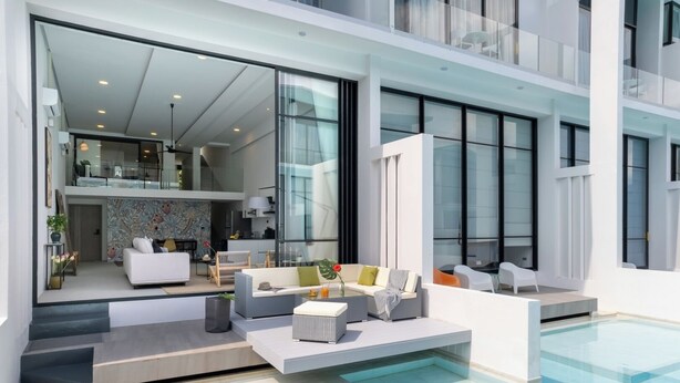 A modern interior with a pool, a living area with sofas and a dining table, and a kitchen visible through glass doors. - Elegant Pool Access Townhouse Near Beach (Bophut)