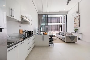 A modern kitchen with white cabinetry, a central island, and a dining area with a sofa and table.