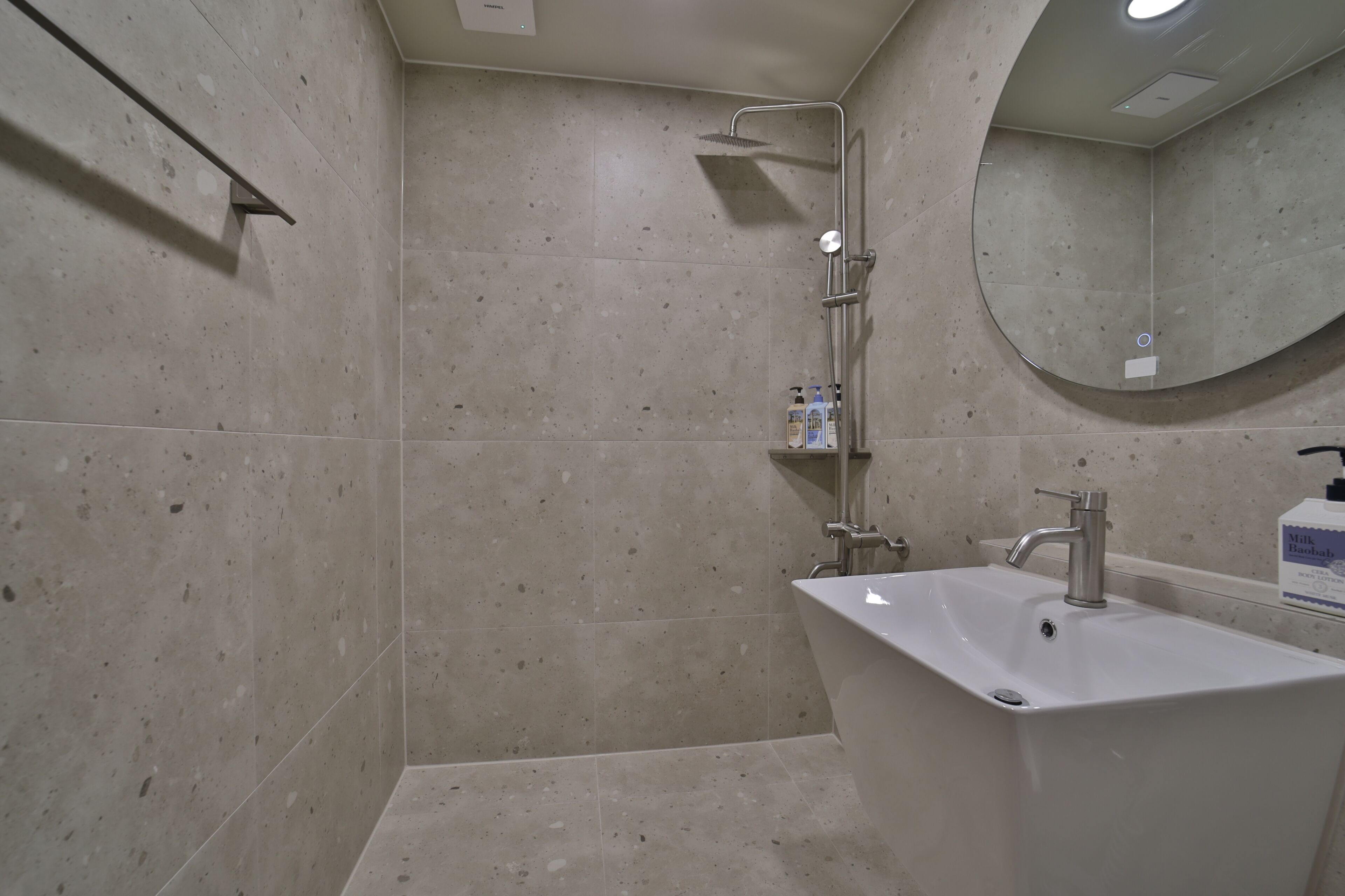Un baño con ducha, lavabo y espejo.