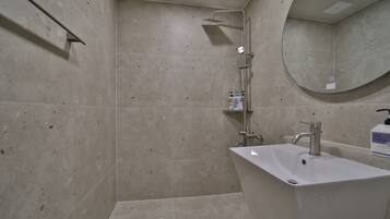 Un baño con ducha, lavabo y espejo.