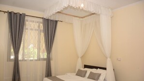 A bedroom with a bed, curtains, a canopy, and a nightstand. - Koriwo Gardens Kikambala Home Away From Home ! (Mtwapa)