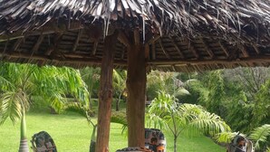 A covered outdoor seating area with a thatched roof, surrounded by greenery. - Koriwo Gardens Kikambala Home Away From Home ! (Mtwapa)