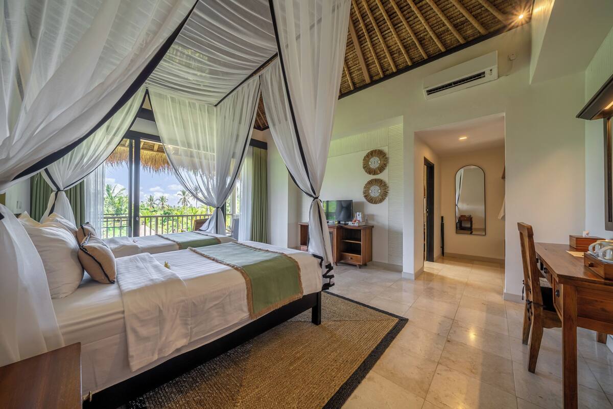 A bedroom with a bed, a TV, a dining table, and a balcony with a view.