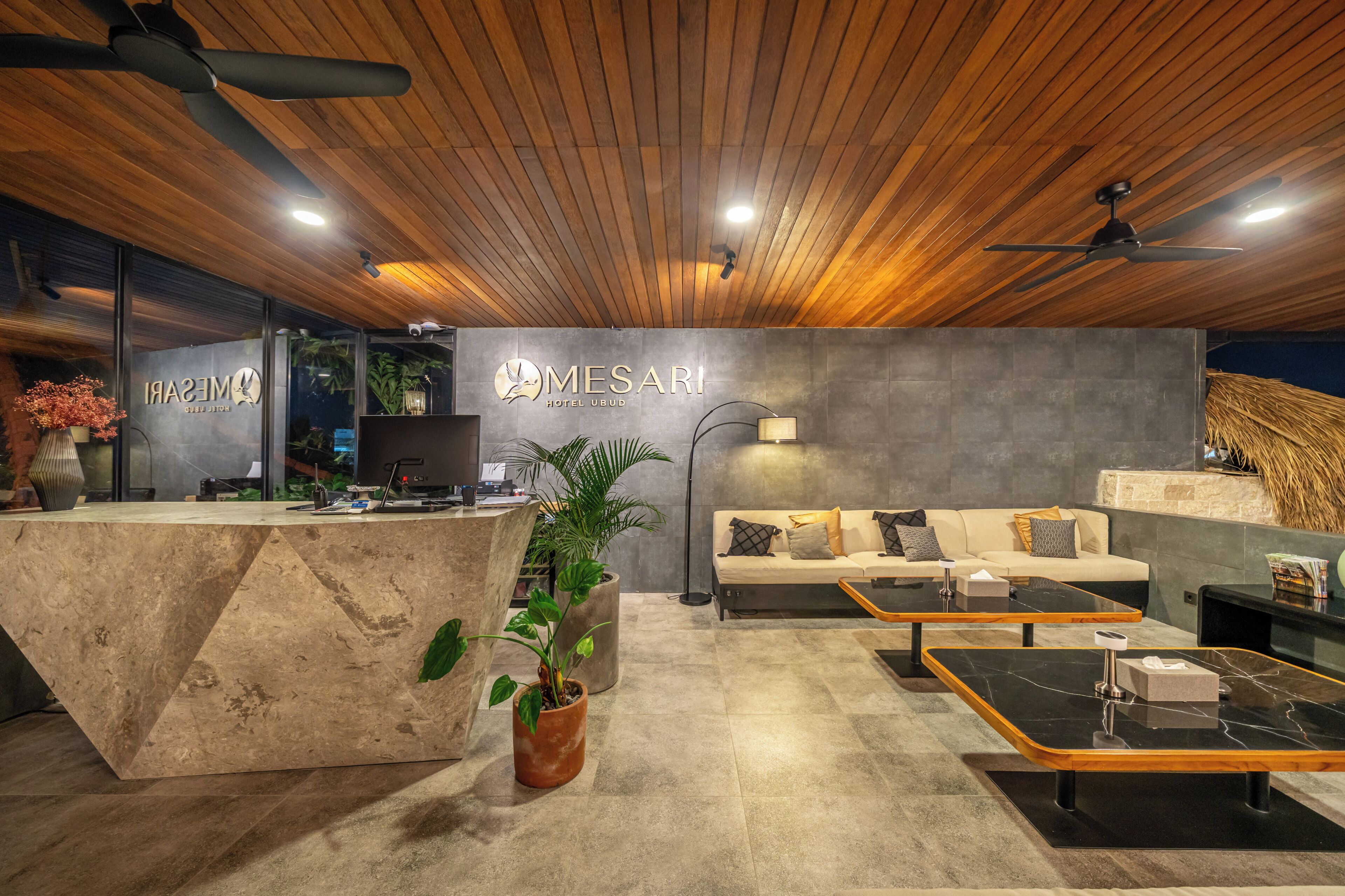 A modern hotel reception with a wooden ceiling, a reception desk, a sofa, and a coffee table.
