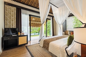 Un dormitorio con cama, televisor, un mueble negro y un ventanal con cortinas.