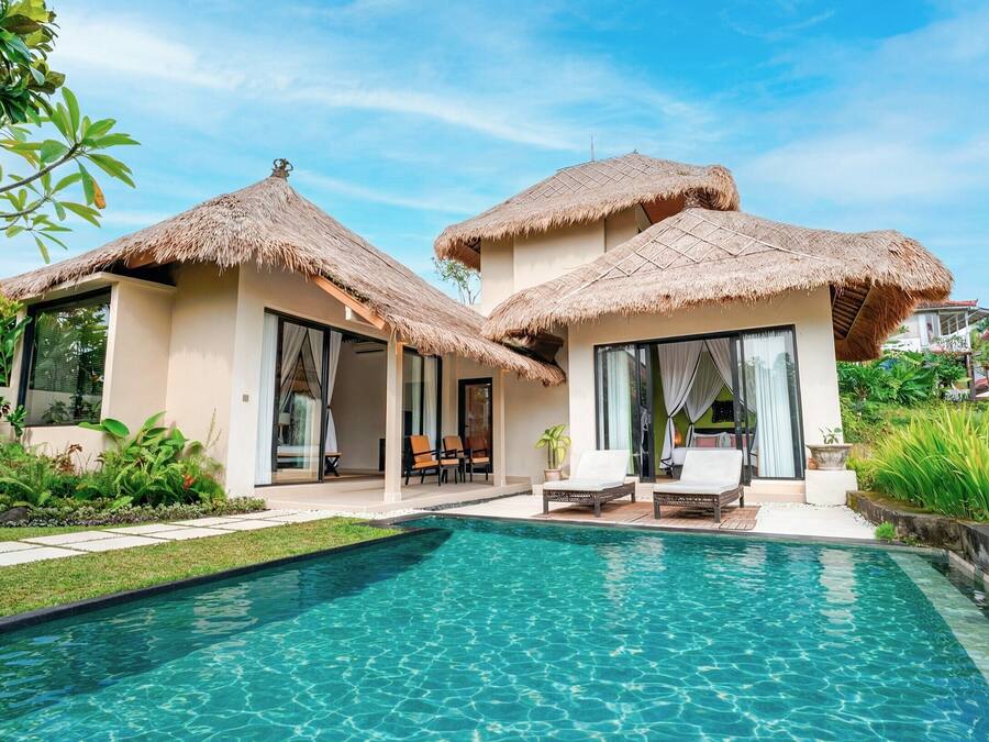 A resort with a swimming pool, thatched-roof structures, and outdoor seating.