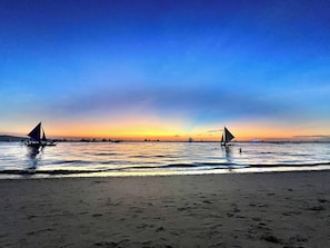 Une plage avec des voiliers, une eau calme et un ciel dégagé.
