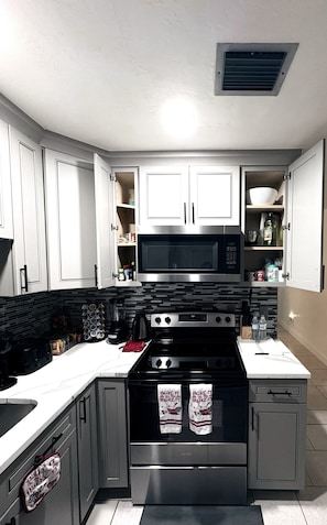 Una cocina con estufa, horno, microondas y alacenas.