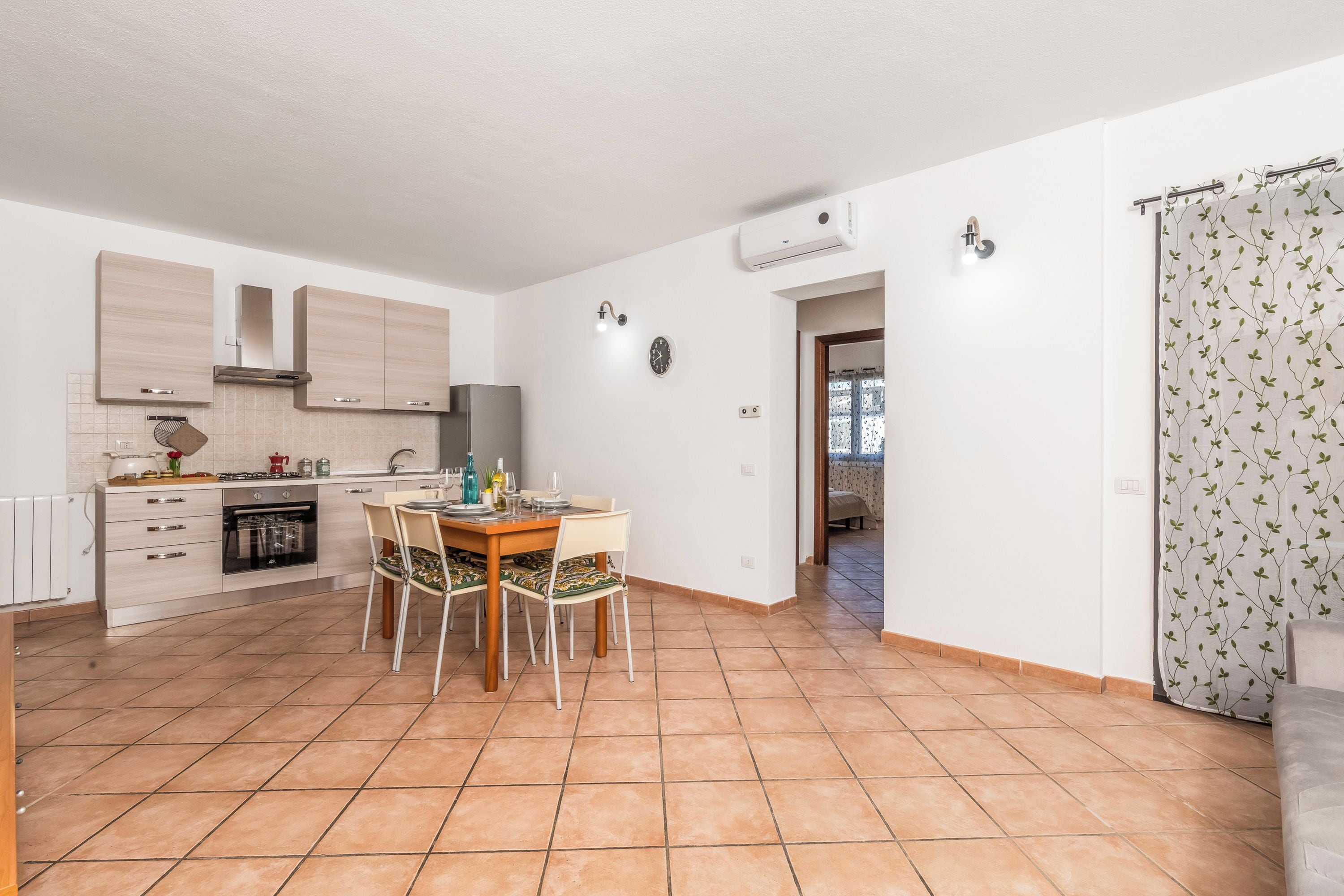 Een moderne keuken met een eethoek, witte wanden en een betegelde vloer.
