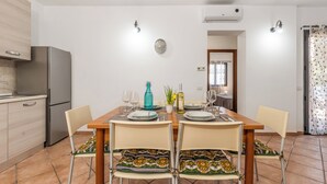 Een moderne keuken met een eethoek, met een roestvrijstalen koelkast, een houten tafel gedekt voor vier personen en een klok aan de muur.