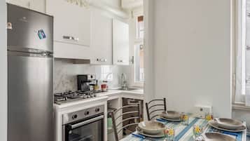 Una cocina moderna con electrodomésticos de acero inoxidable, armarios blancos y una zona de comedor preparada para cuatro personas.