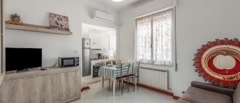 Un espacio habitable compacto con kitchenette, comedor y sofá.