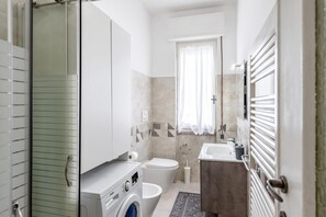 A modern bathroom with a washing machine, toilet, and sink. - Casa Tolly Rapallo (Rapallo)