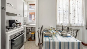 A kitchen with white cabinets, a stove, and a dining table set with plates and bowls.