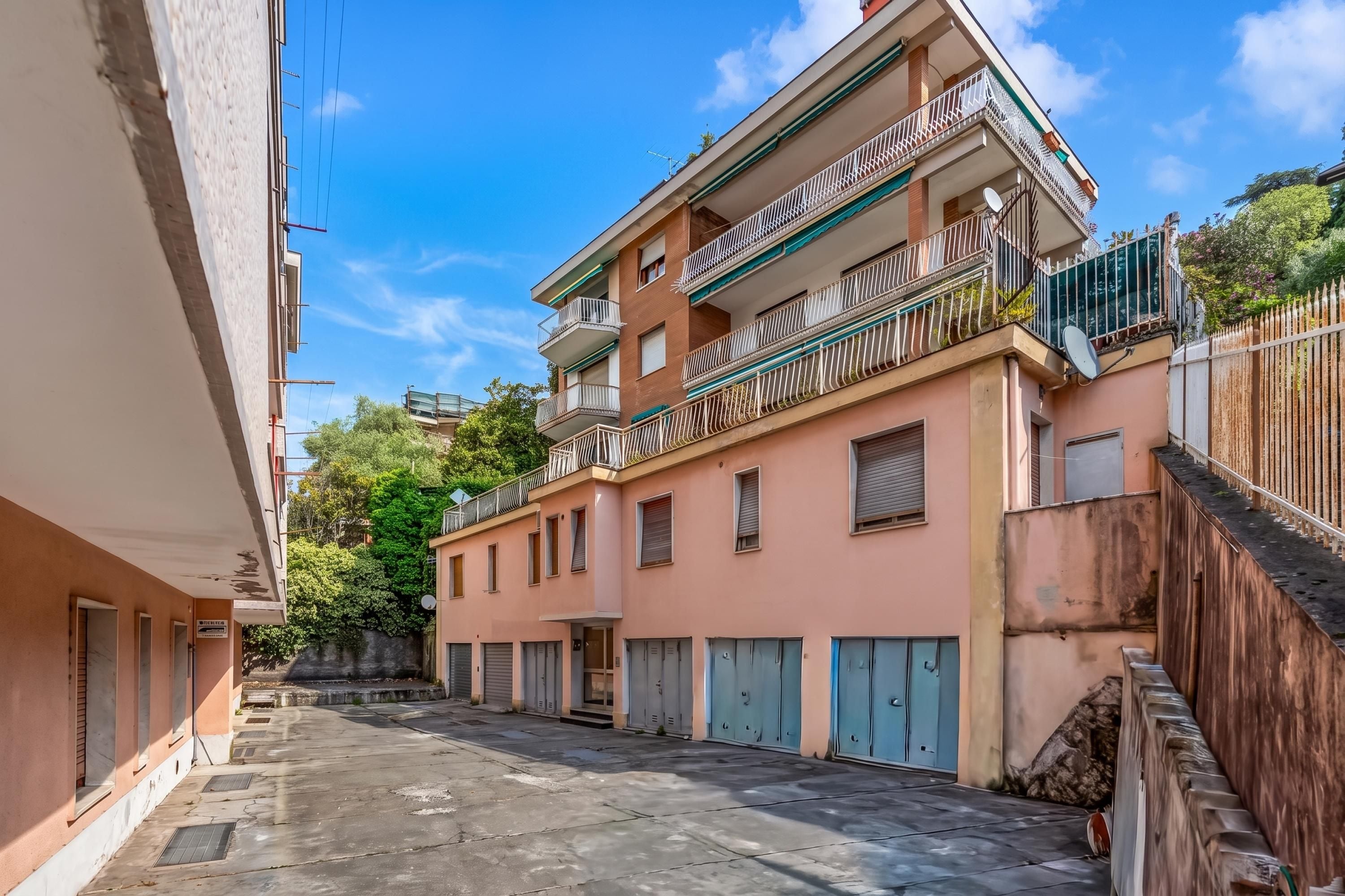 Uma rua estreita com edifícios em ambos os lados, com varandas e antenas parabólicas.