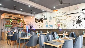 A restaurant with a herringbone floor pattern, modern furniture, and a wall mural.