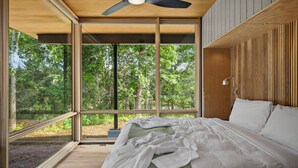A bedroom with a large window, a ceiling fan, and a bed with pillows. - 3 Luxury Cabins on 40 wooded acres @ Oak & Ember Luxury Resort (Wisconsin Dells)