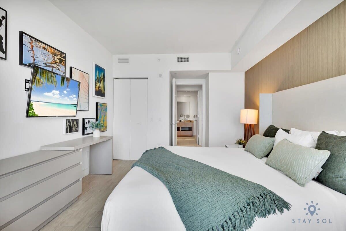 Una habitación de hotel moderna con una cama grande, un escritorio y vista a la playa.