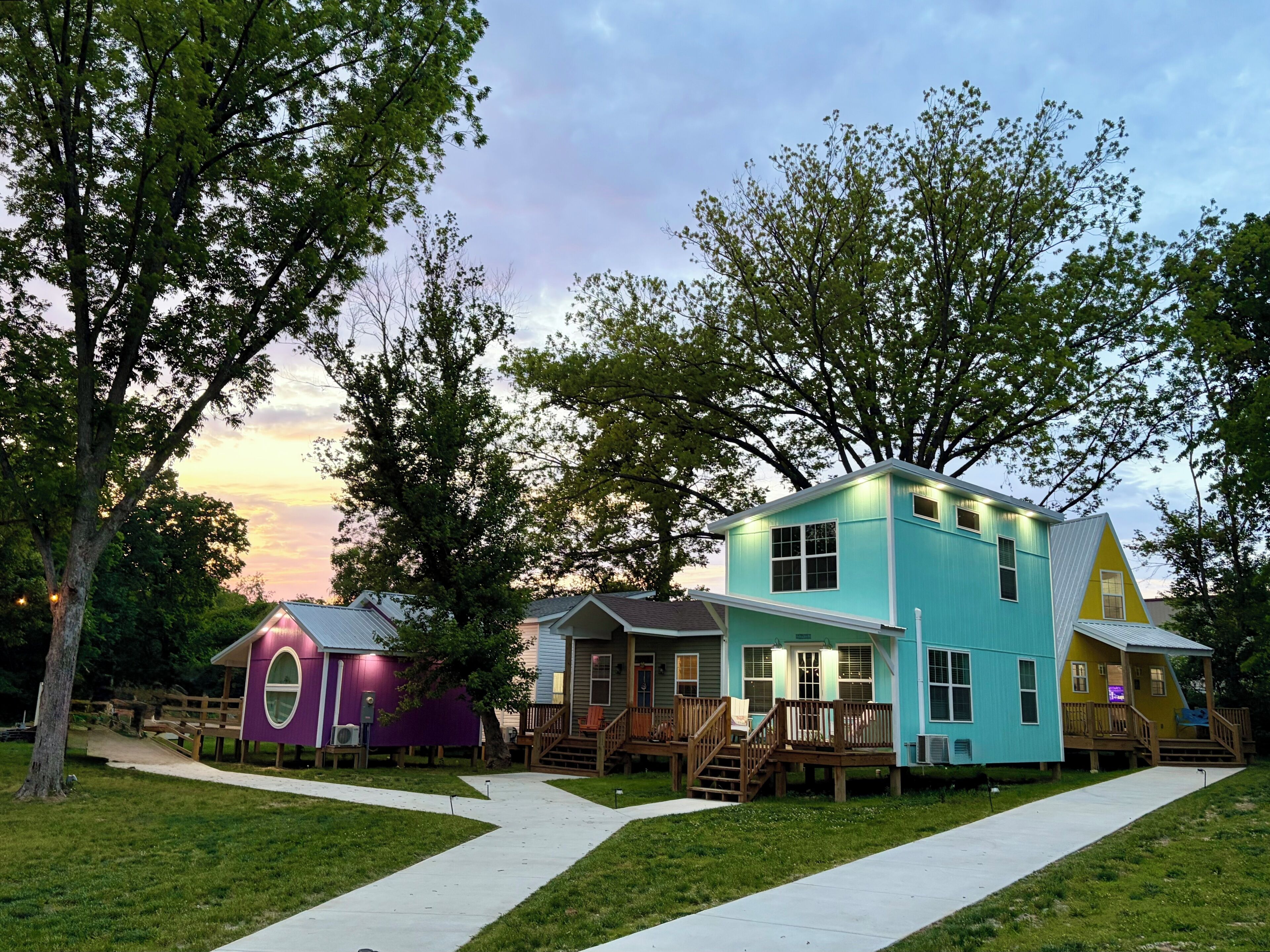 A row of colorful houses with a clear sky and trees in the background.