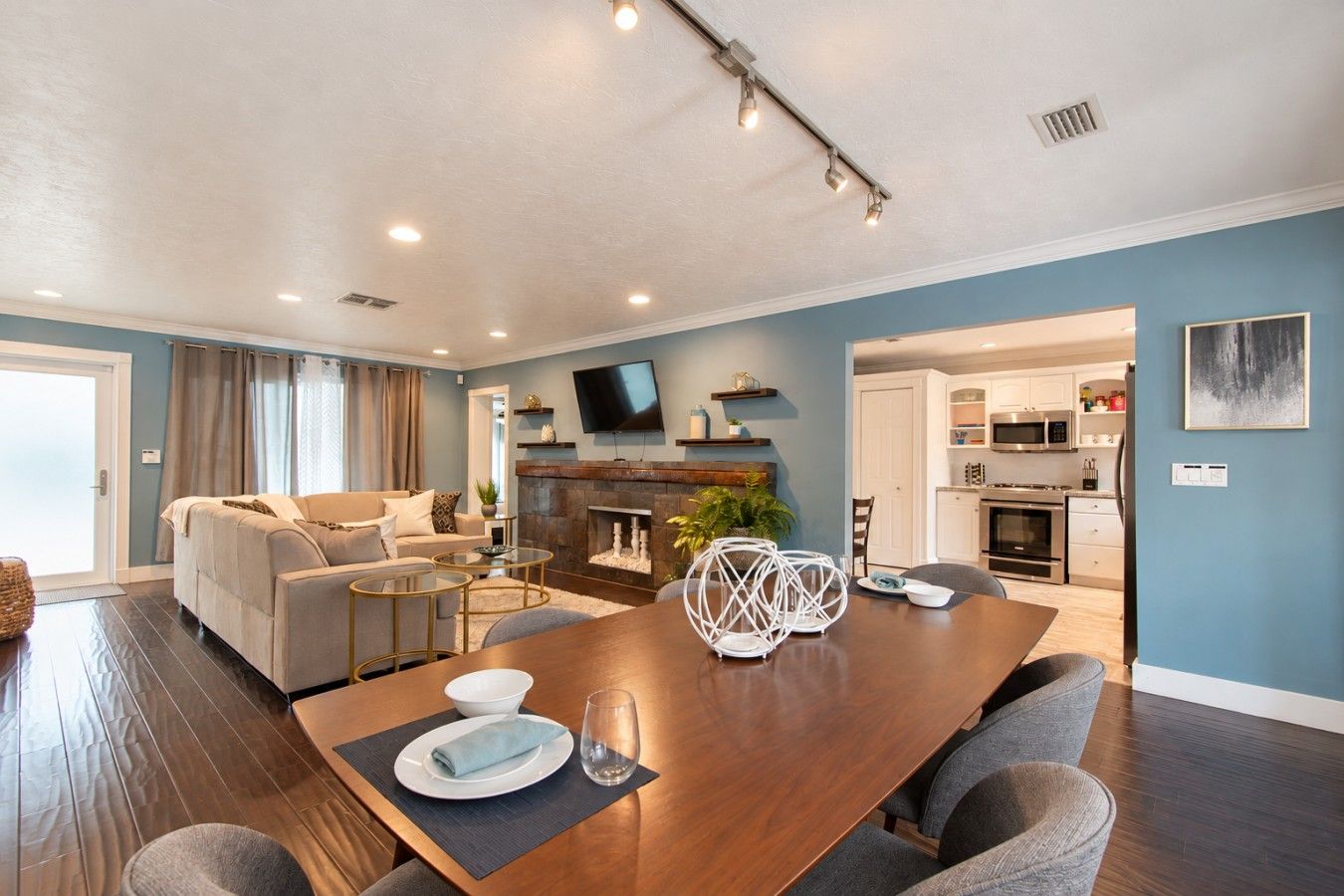 A modern living room with a wooden dining table, sofas, and a fireplace.