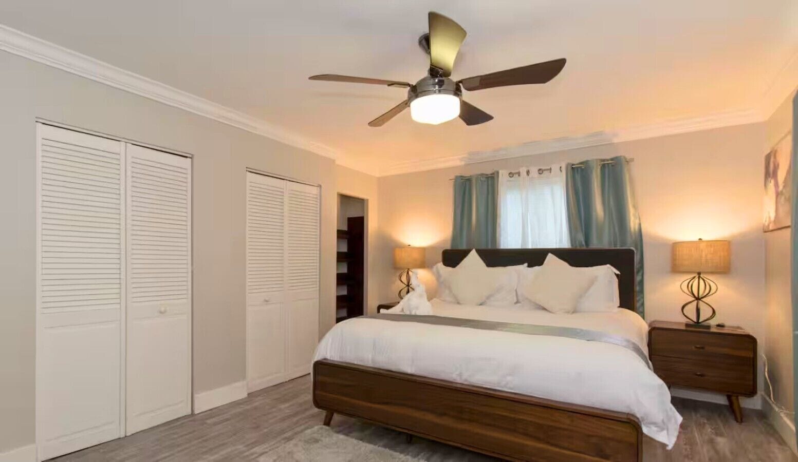 Ein Schlafzimmer mit einem Bett, zwei Nachttischen, einem Deckenventilator und einem Kleiderschrank.