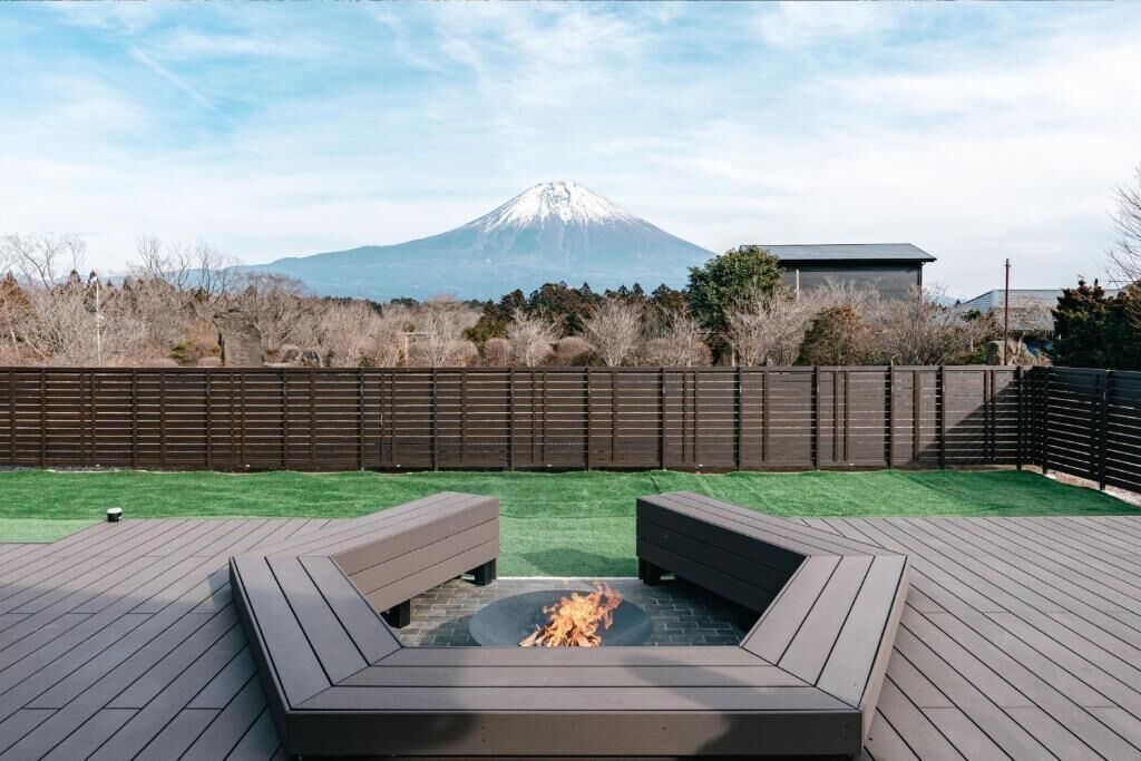 Une terrasse avec un foyer, une vue sur une montagne et une clôture en bois.